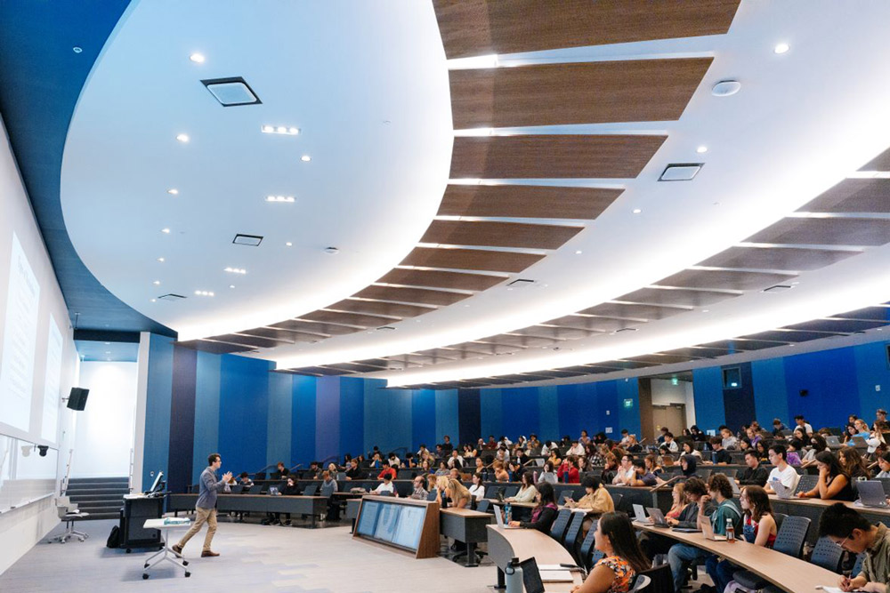 A wide angle photo of a lecturer standing in front of a large modern classroom